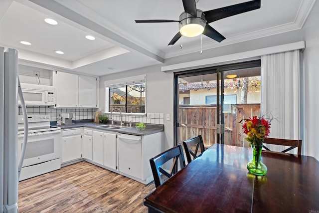 kitchen featuring light wood-type flooring, tasteful backsplash, white appliances, sink, and white cabinetry