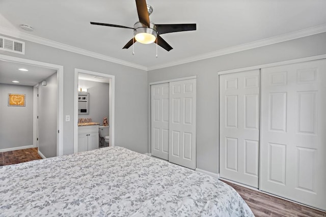 bedroom with ensuite bath, ceiling fan, crown molding, hardwood / wood-style flooring, and multiple closets