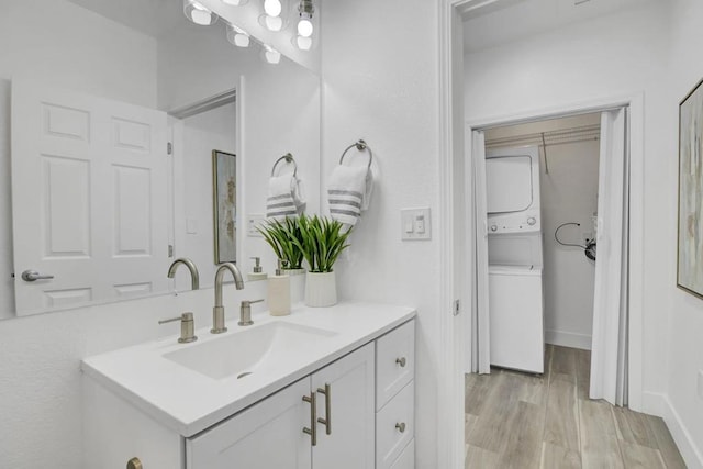 bathroom featuring stacked washer / dryer, vanity, and wood-type flooring