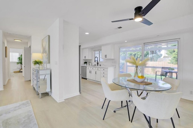 dining area with light wood-type flooring, ceiling fan, and sink