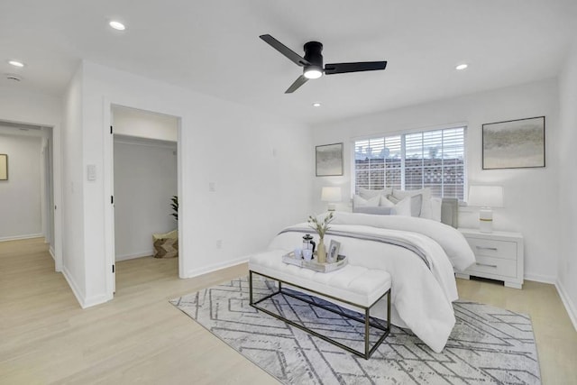 bedroom featuring a walk in closet, a closet, ceiling fan, and light hardwood / wood-style floors