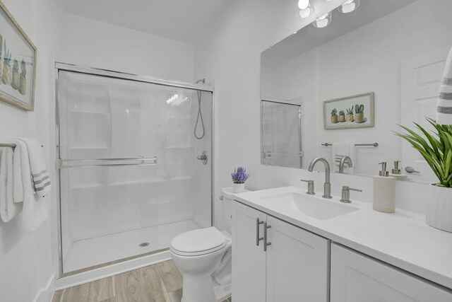 bathroom with toilet, hardwood / wood-style flooring, an enclosed shower, and vanity