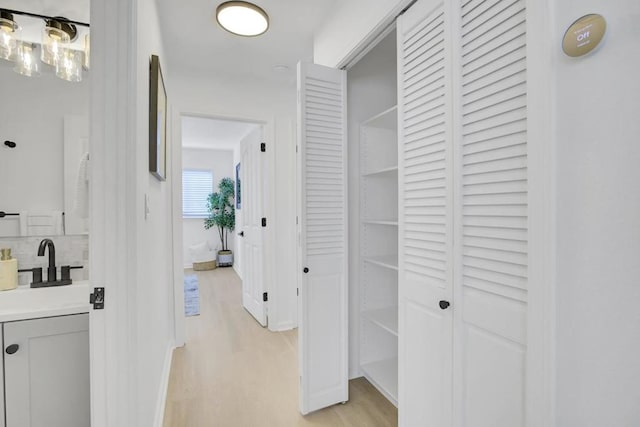 hallway with sink and light hardwood / wood-style flooring