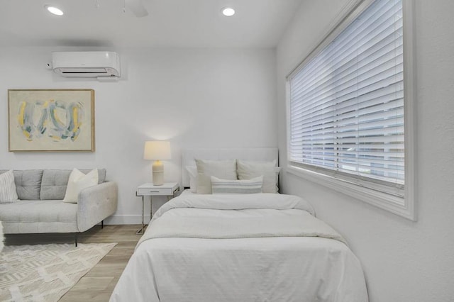 bedroom featuring ceiling fan, light wood-type flooring, and a wall unit AC