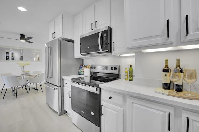 kitchen featuring white cabinets, stainless steel appliances, light stone counters, and ceiling fan