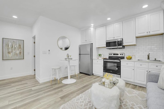 kitchen featuring stainless steel appliances, white cabinets, and tasteful backsplash