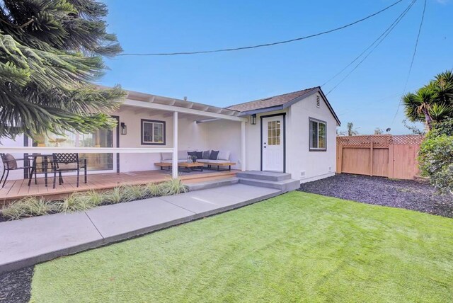 back of property with an outdoor hangout area, a deck, and a lawn