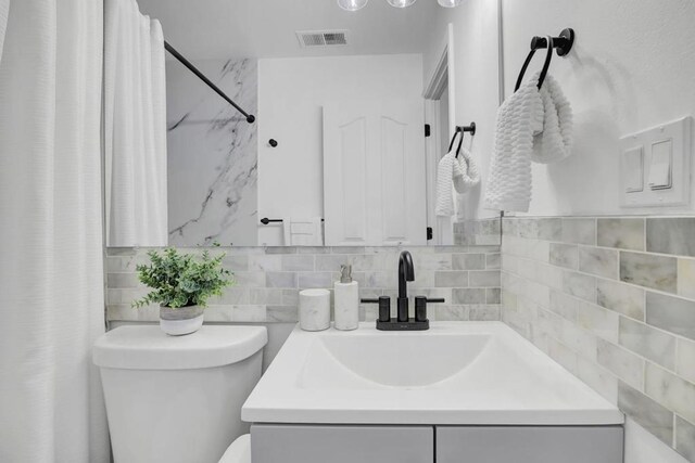 bathroom with backsplash, vanity, and toilet