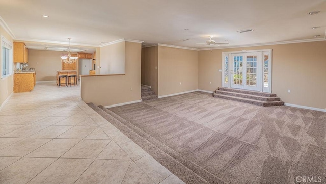 spare room featuring ceiling fan with notable chandelier, light colored carpet, and crown molding