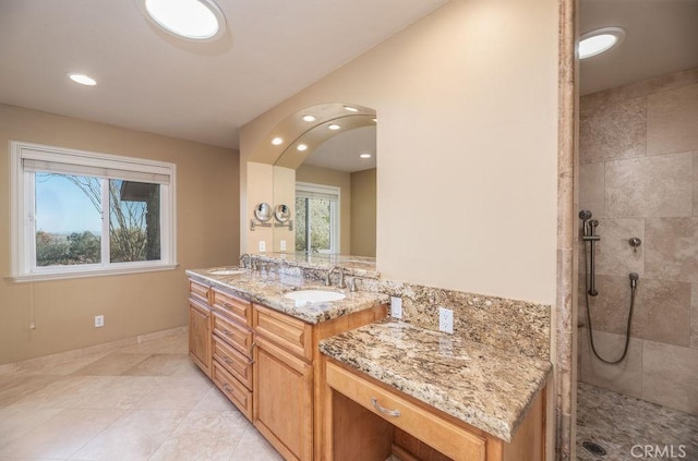 bathroom with tile patterned flooring, vanity, and tiled shower