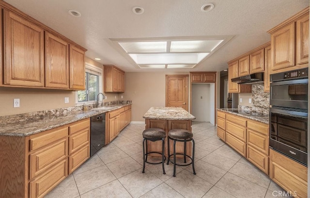 kitchen featuring light stone countertops, a kitchen breakfast bar, black appliances, sink, and a kitchen island