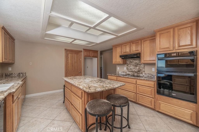 kitchen featuring black appliances, a kitchen island, light tile patterned flooring, and light stone countertops