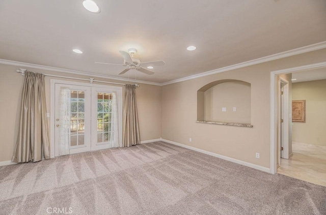 spare room with ceiling fan, light colored carpet, crown molding, and french doors