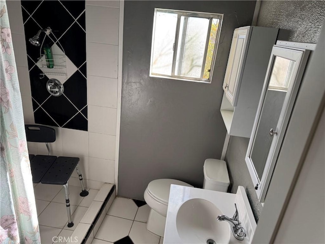 bathroom with baseboard heating, sink, tile patterned flooring, toilet, and curtained shower