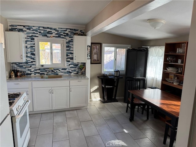 kitchen featuring backsplash, white cabinetry, sink, and white range