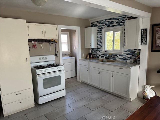 kitchen featuring washer / dryer, white cabinetry, and gas range gas stove