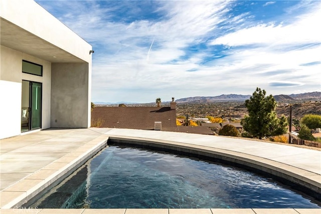 view of swimming pool with a mountain view and a jacuzzi