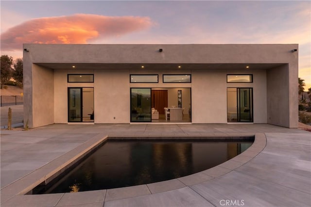 back house at dusk featuring a patio area