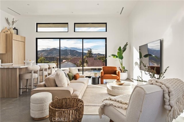 living room featuring a mountain view, plenty of natural light, and concrete flooring