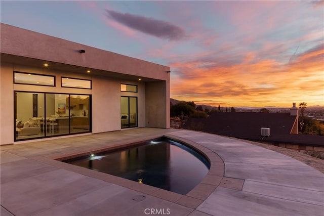 pool at dusk with a patio