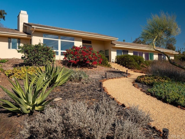 back of property with a chimney and stucco siding