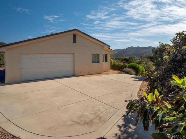 view of home's exterior featuring a detached garage, a mountain view, and stucco siding