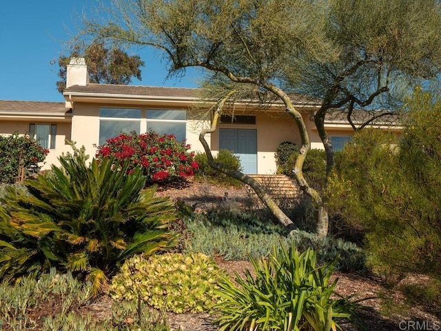 view of front of home with a chimney and stucco siding