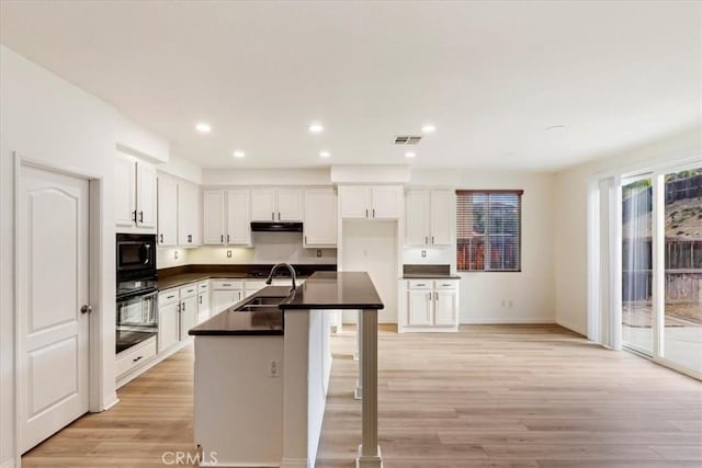 kitchen with white cabinets, sink, light hardwood / wood-style floors, and black appliances