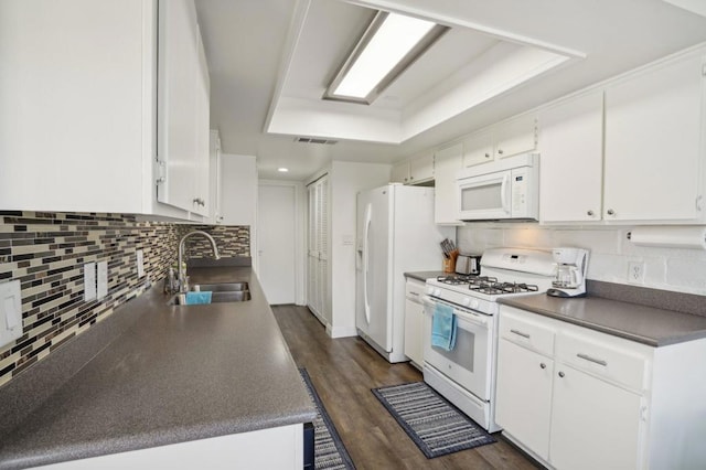 kitchen featuring white appliances, a tray ceiling, sink, white cabinets, and dark hardwood / wood-style floors