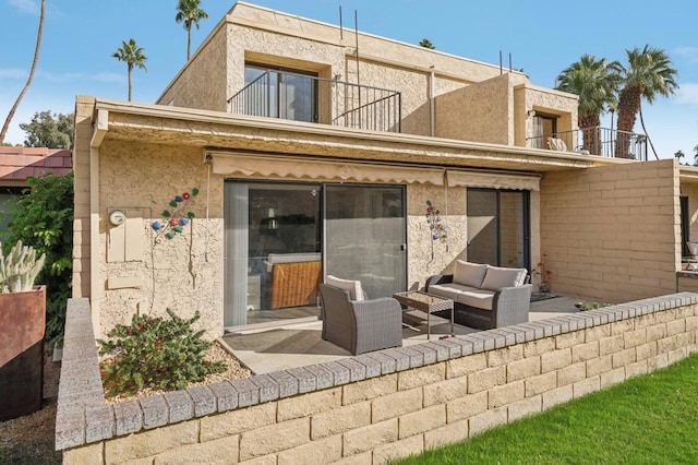 back of property with outdoor lounge area, a patio area, and a balcony