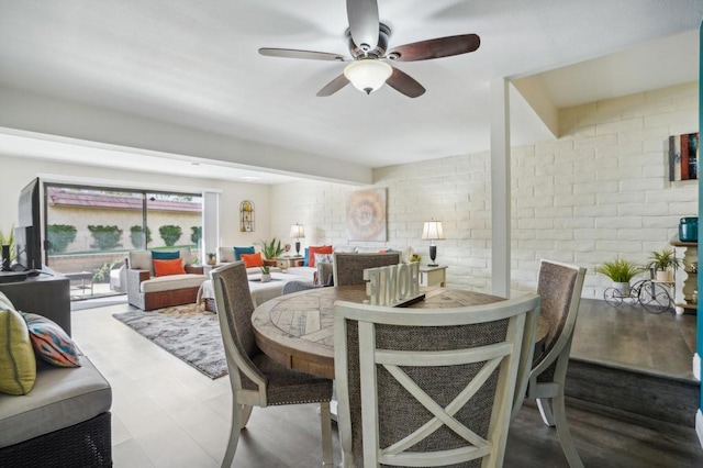 dining room with hardwood / wood-style flooring, ceiling fan, and brick wall