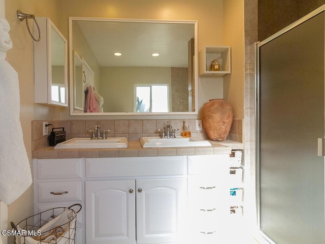 bathroom with vanity, a shower with shower door, and backsplash