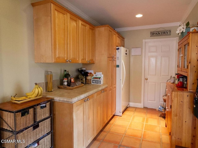 kitchen with light brown cabinetry, white fridge, ornamental molding, and light tile patterned flooring