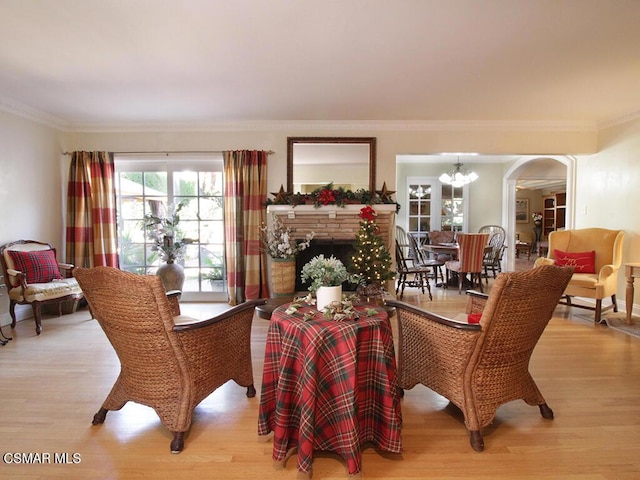 dining room featuring a stone fireplace, a chandelier, light hardwood / wood-style floors, and ornamental molding