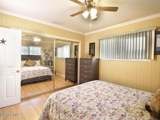 bedroom with light hardwood / wood-style floors, a closet, ornamental molding, and ceiling fan