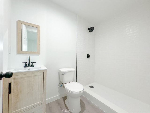 bathroom featuring tiled shower, hardwood / wood-style floors, vanity, and toilet