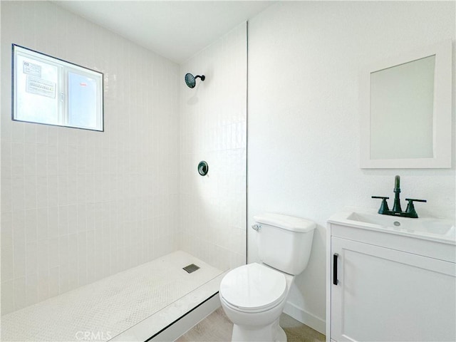 bathroom featuring tiled shower, vanity, and toilet