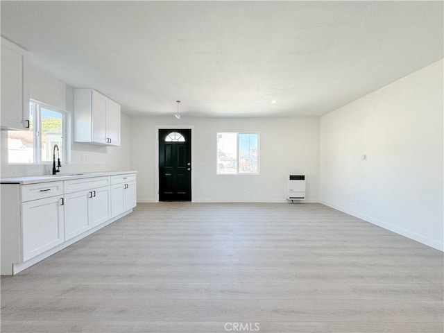 unfurnished living room featuring heating unit, light hardwood / wood-style flooring, and a healthy amount of sunlight