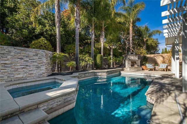 view of pool with an in ground hot tub, an outdoor stone fireplace, and a patio area