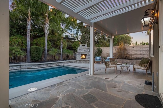 pool at dusk with an outdoor living space with a fireplace and a patio