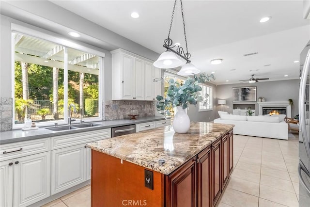 kitchen featuring decorative backsplash, sink, decorative light fixtures, white cabinets, and a center island