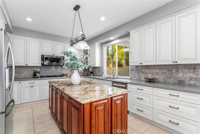 kitchen featuring appliances with stainless steel finishes, sink, pendant lighting, white cabinets, and a center island