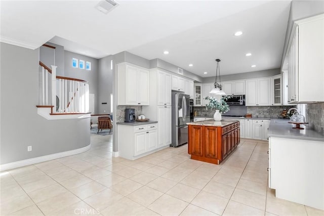 kitchen featuring hanging light fixtures, a kitchen island, backsplash, white cabinets, and appliances with stainless steel finishes