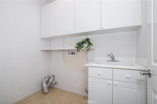 laundry room featuring cabinets, light tile patterned floors, sink, and hookup for a washing machine