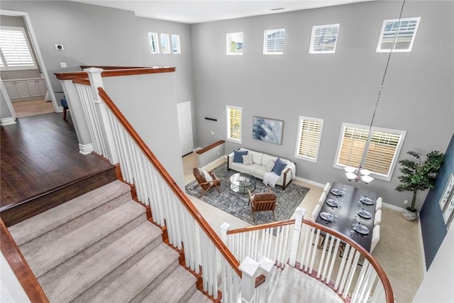 staircase featuring a chandelier, plenty of natural light, hardwood / wood-style floors, and a high ceiling