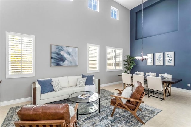 living room featuring plenty of natural light, a towering ceiling, and a chandelier