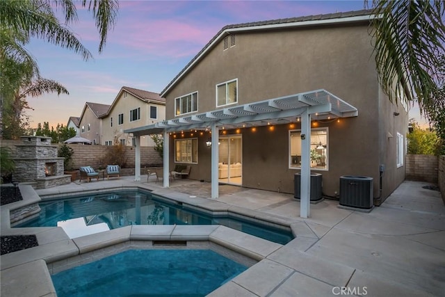 pool at dusk featuring a pergola, a hot tub, an outdoor stone fireplace, central air condition unit, and a patio area