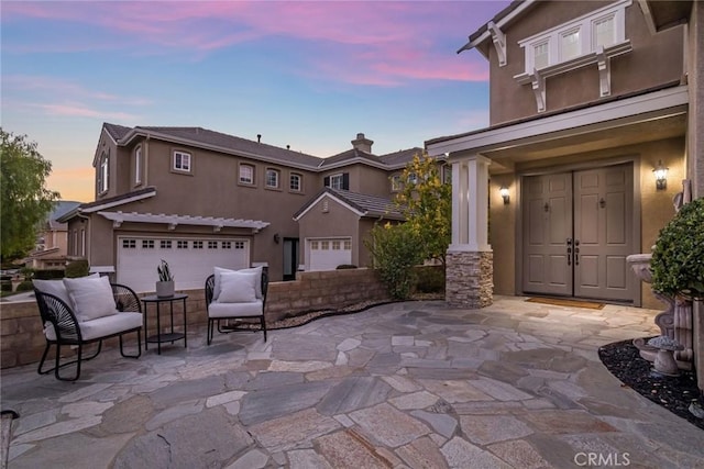 patio terrace at dusk featuring a garage