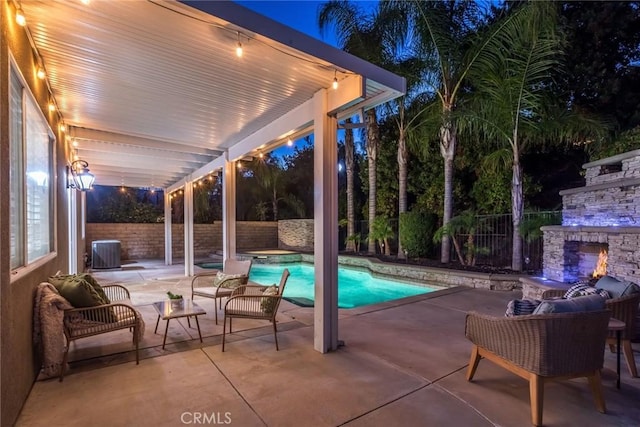 view of swimming pool featuring cooling unit, a patio, and an outdoor stone fireplace