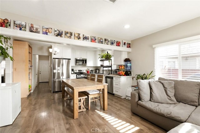 kitchen with white cabinets, sink, a notable chandelier, wood-type flooring, and stainless steel appliances